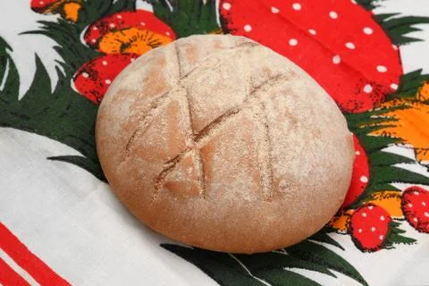 A loaf of round bread with a pattern on a bright tablecloth Stock Photos