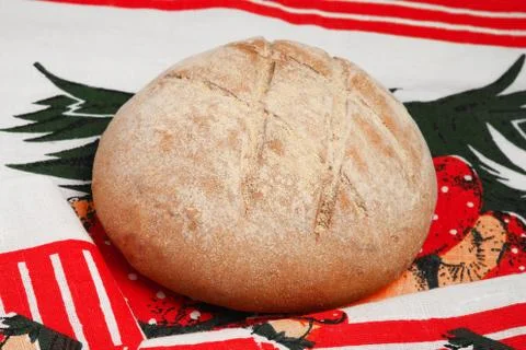 A loaf of round bread with a pattern on a bright tablecloth Stock Photos