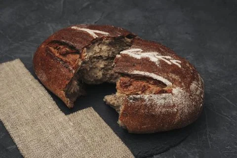 A loaf of round warm bread broken in half. Freshly baked dark grain bread, br Stock-Fotos