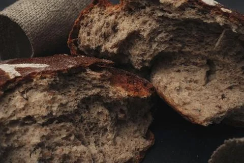 A loaf of round warm bread broken in half. Freshly baked dark grain bread, br Stock Photos