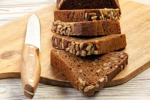 Loaf of rye bread and a pair of slices cut with a knife Stock Photos