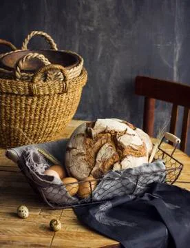Loaf of rye bread in a basket with chicken eggs on the table Stock Photos