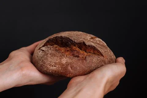 A loaf of rye bread in his hands on a black background. Fotos de archivo