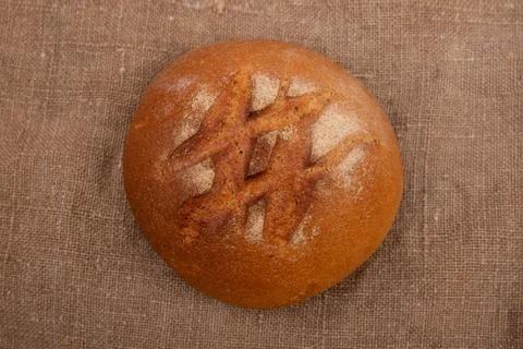 Loaf of rye bread on rustic wooden table with burlap close-up Stock Photos