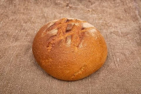 Loaf of rye bread on rustic wooden table with burlap close-up Stock Photos