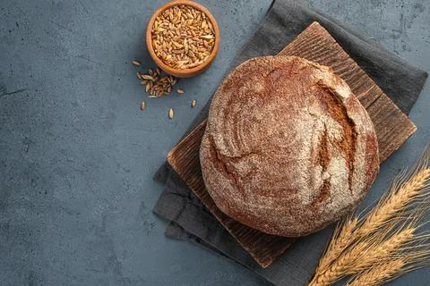 A loaf of rye bread with wheat and ears on a graphite background. Stock Photos
