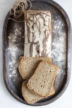 Loaf of sliced rye bread on old wooden tray. Stock Photos
