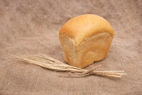Loaf of wheat bread on rustic wooden table with burlap close-up Stock Photos