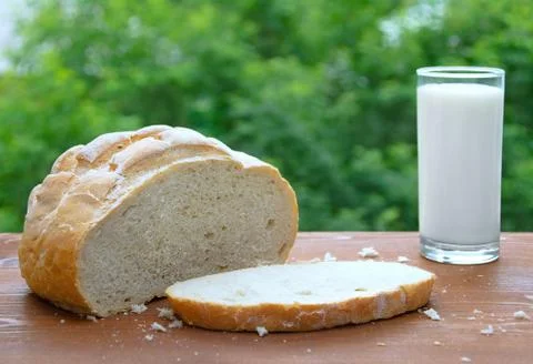 Loaf of white bread, cut a loaf of bread and milk in a glass. On a wooden bac Stock Photos