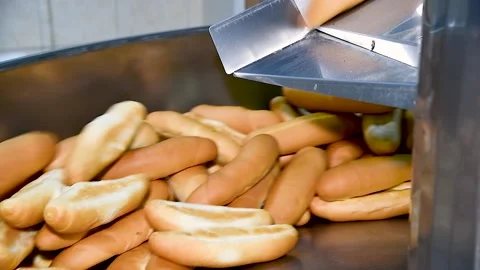 Loafs of bread in a bakery on an automated conveyor belt Stockbeeldmateriaal 239983569