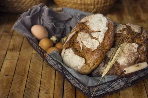 Loafs of rye bread in a basket with chicken eggs on the table Stock Photos