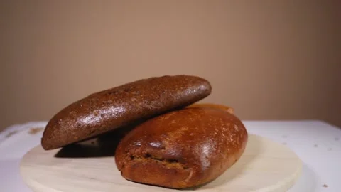 Loafs of tasty fresh baked bread on a wooden rotating plate Stock Footage 124385383