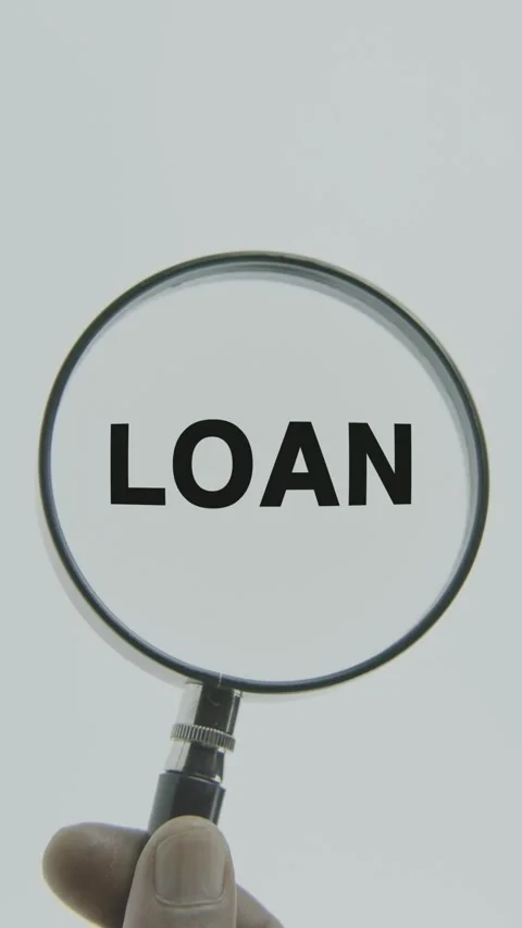 Loan text or word highlighted by a magnifying glass in a hand on a white Stock Footage 303476723