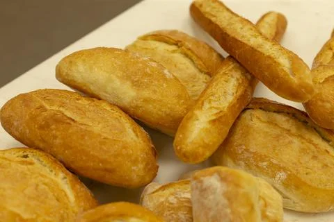Loaves of bread arranged on a flour-dusted surface in a bakery setting, fresh. Stockfoto's