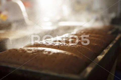 Loaves of bread being sprayed with water Stock Photos