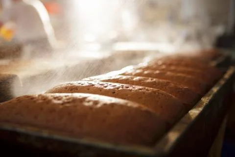 Loaves of bread being sprayed with water Stock Photos