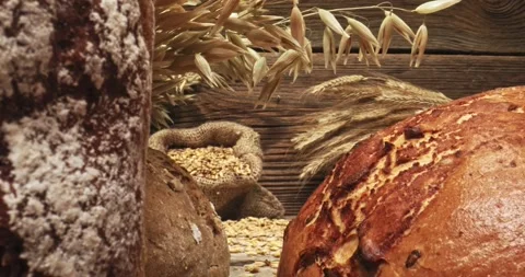 Loaves of bread with grains and ears on wooden table 動画素材 243887664