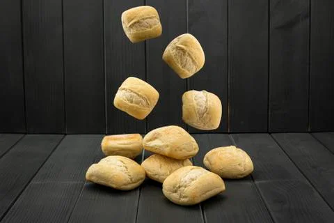 Loaves of wheat bread falling on a gray wooden table Stock Photos