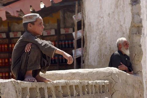 A local Afghan boy and an old man watch as a patrol of International Secur... Stock Photos