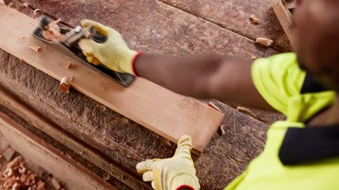 Local African carpenter using metal hand plane on wooden plank in workshop Stock Footage 346733800