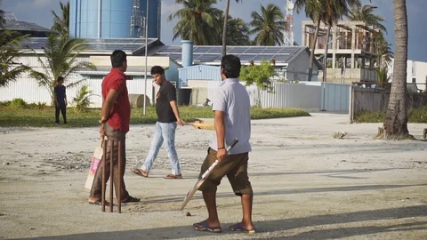 Local cricketers lined up to swing at game on Maafushi Island, in slow motion Vidéo 75325831