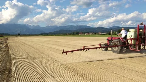 Local farmer spraying the field with non toxic chemicals. Farmer on a tractor Stock Footage 137666552