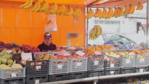 Local Fruit Vendor Sitting Behind Colorful Outdoor Market Stall Stock Footage 335567207