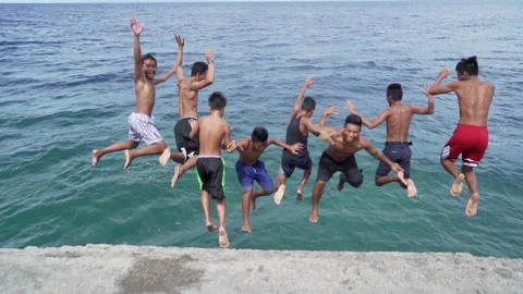 Local group jumping from pier into the blue ocean Video stock 231755387