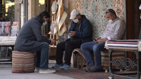 Local guys sit on designed chairs selling carpets in shops Stock Footage 150139100