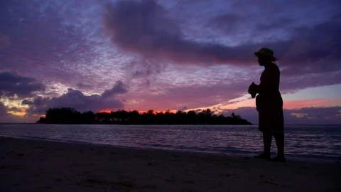 A local islander blows a conch shell during sunset on a scenic tropical island i Stock Footage 73451465