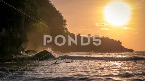 Local Kids surf on Waves in Sunset light, Beautiful Crystal Bay, Nusa Penid.. Stock Photos