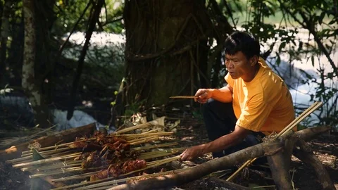 Local Lao man preparing meat on BBQ in natural setting in Luang Prabang Stock Footage 104119844