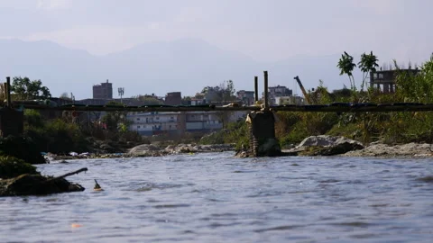 Local made old bamboo bridge on a flowing river water Stock Footage 285697091