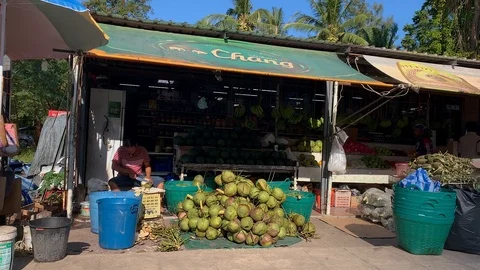 Local Man cutting Coconuts infront of a Market Stock Footage 124022151