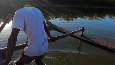 A local man pushes typical Madagascar canoe into waters of Morondava River Stock Footage 308808813