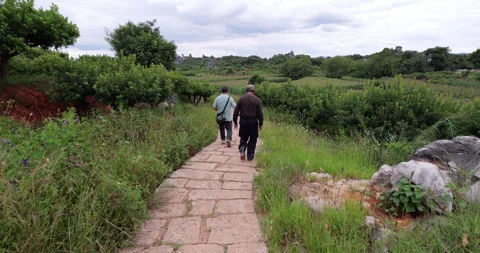Local men walking at paved rural path at Shilin Stone Forest outskirts Stock Footage 329491483