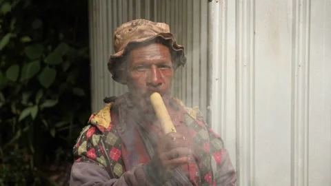 Local papuan man with red teeth smoking a tobacco from a pipe. Papua New Guinea Видео 310860740