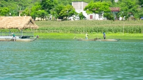 Local people float on river boat with paddle past village Stock Footage 100190511