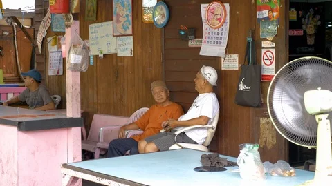 Local Thai men sitting behind market stall in Bangkok and talking, slow Stock Footage 116265880