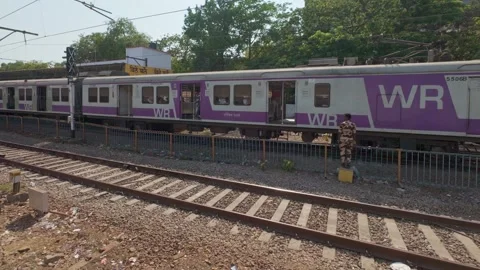 Local train arrives at a platform of the railway station in Mumbai Stock Footage 313532888