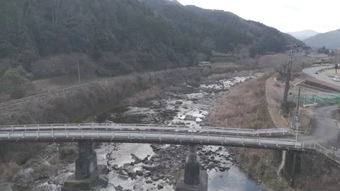 Local Train Crossing a Railway Bridge in Rural Japan – 4K Aerial Static Shot Stock Footage 325408459