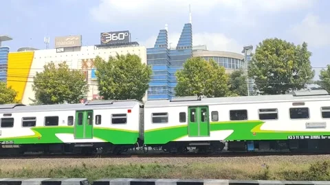 Local train passing by with a mall in the background in Surabaya Indonesia Stock Footage 238998823