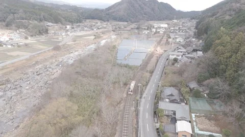 Local Train Passing Through Rural Japanese Countryside – 4K Aerial Static Shot Stock Footage 325408376