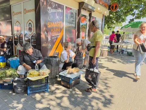 Local vendors interact with customers at a bustling market in sunny weather Stock Photos