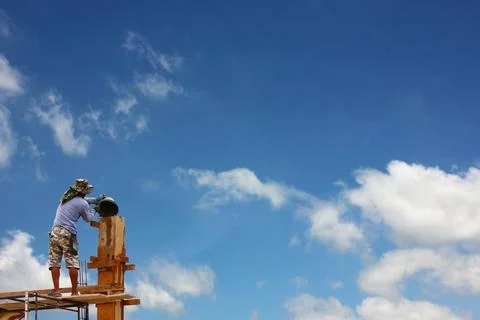 A local worker stood on scaffolding without protective gear pouring cement .. Fotos de archivo