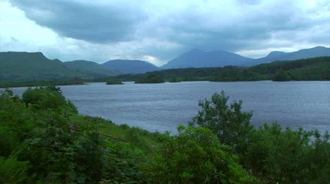 Loch with high mountain, trees and water surface affected by wind Stock Footage 39392604