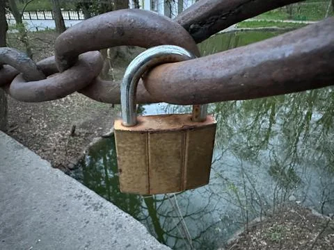 The lock is attached to a rusty chain. A small padlock is attached to the c.. Stock Photos