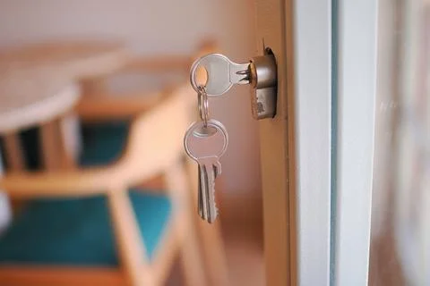 The lock has keys that are currently inserted into the keyhole of the door Stock Photos
