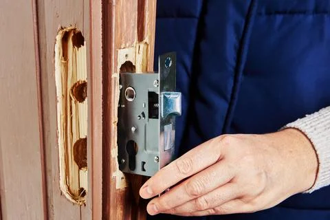 Lock technician aligning lever lock with door frame. Stock Photos