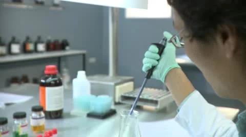Lockdown, CU of a lab tech using a dropper to put a sample in a vial, focus on Stock Footage 10702130